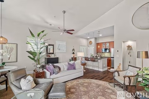 A living room with a grey couch and a fan.