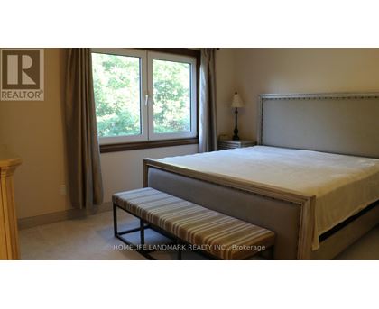 A bedroom with a bed, bench, and window.