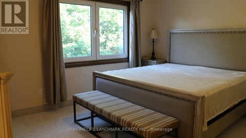 A bedroom with a bed, bench, and window.