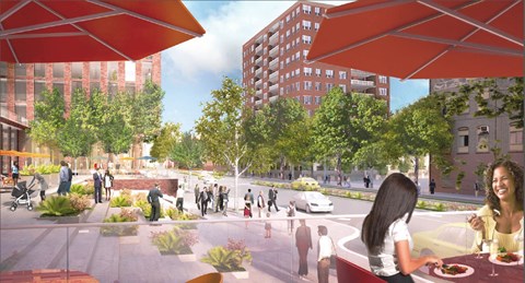 A woman is sitting at a table in a city plaza with people walking around her.