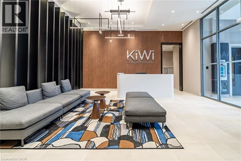 A modern living room with a grey sofa and a wooden wall with the words "Kiwi Condominiums" on it.