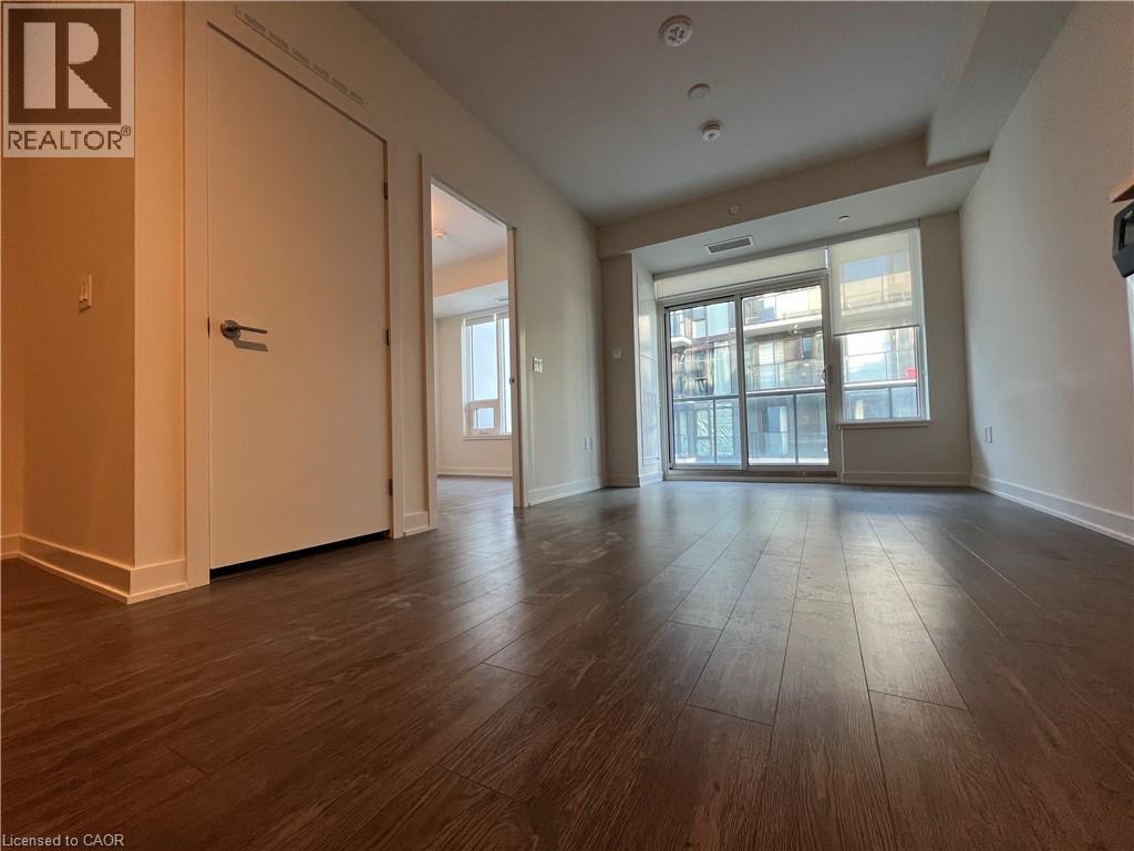 A spacious room with wooden flooring and a large window.