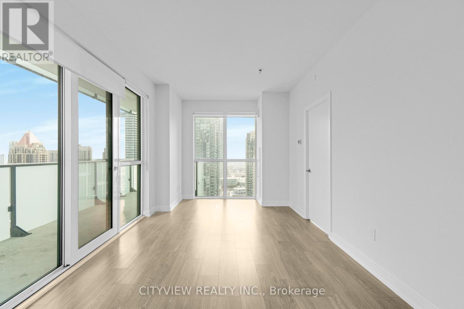 A spacious room with a view of the cityscape through the windows.
