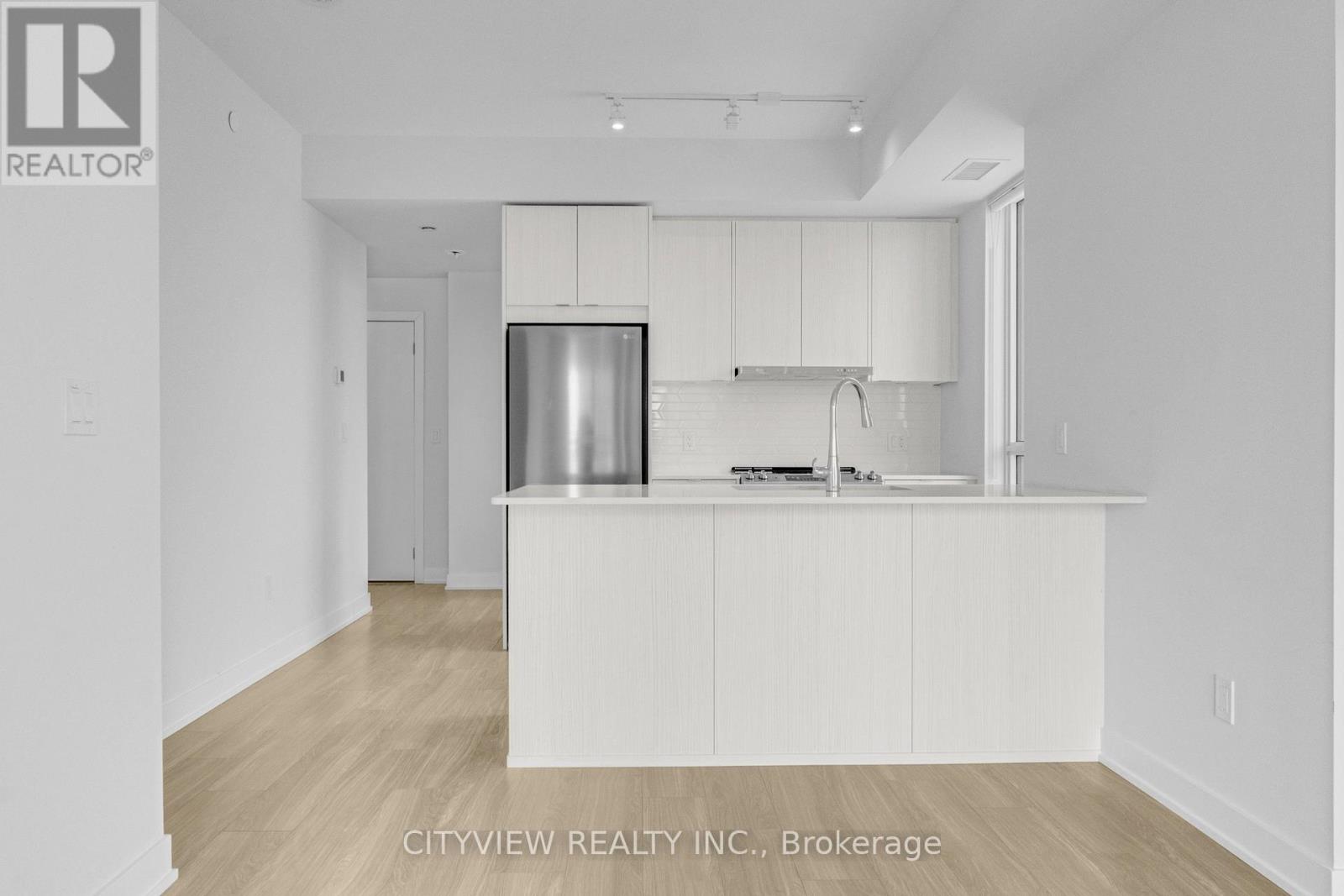 A kitchen with white cabinets and a refrigerator.