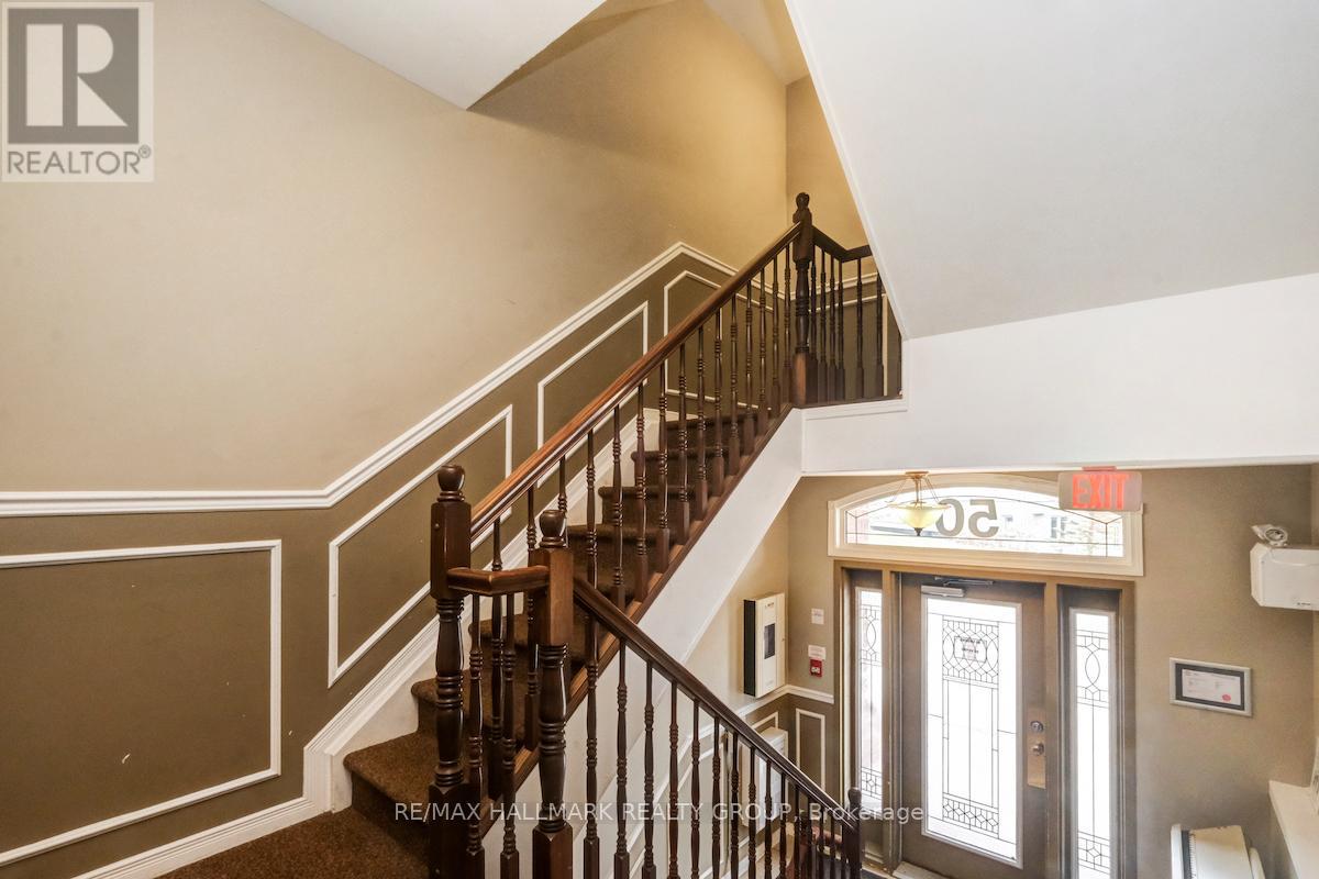 A staircase with a wooden banister and a glass door with a sign above it.