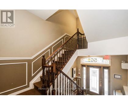 A staircase with a wooden banister and a glass door with a sign above it.