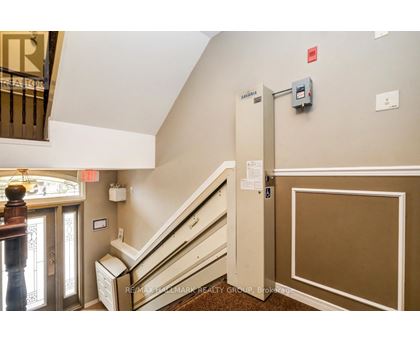 A hallway with a staircase and a wall-mounted elevator control panel.