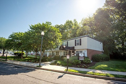 A sunny day in a residential area with a house and trees.