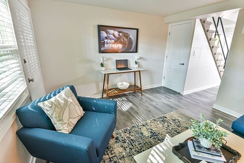 A blue couch with a pillow sits in a living room with a fireplace and a painting on the wall.