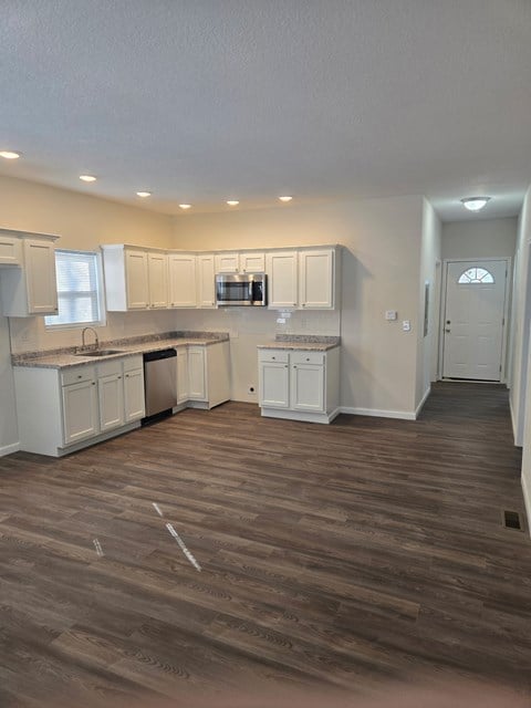 A kitchen with white cabinets and a wooden floor.