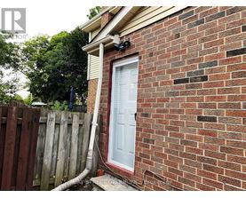 A red brick house with a white door and a white pipe coming out of the ground.
