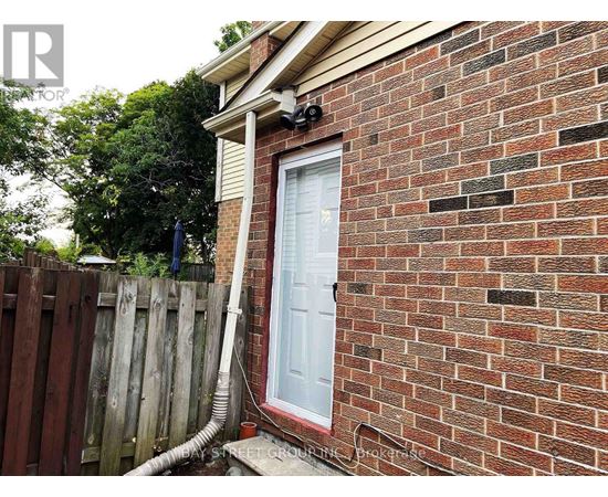 A red brick house with a white door and a white pipe coming out of the ground.