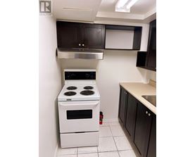 A white stove in a kitchen with black cabinets.