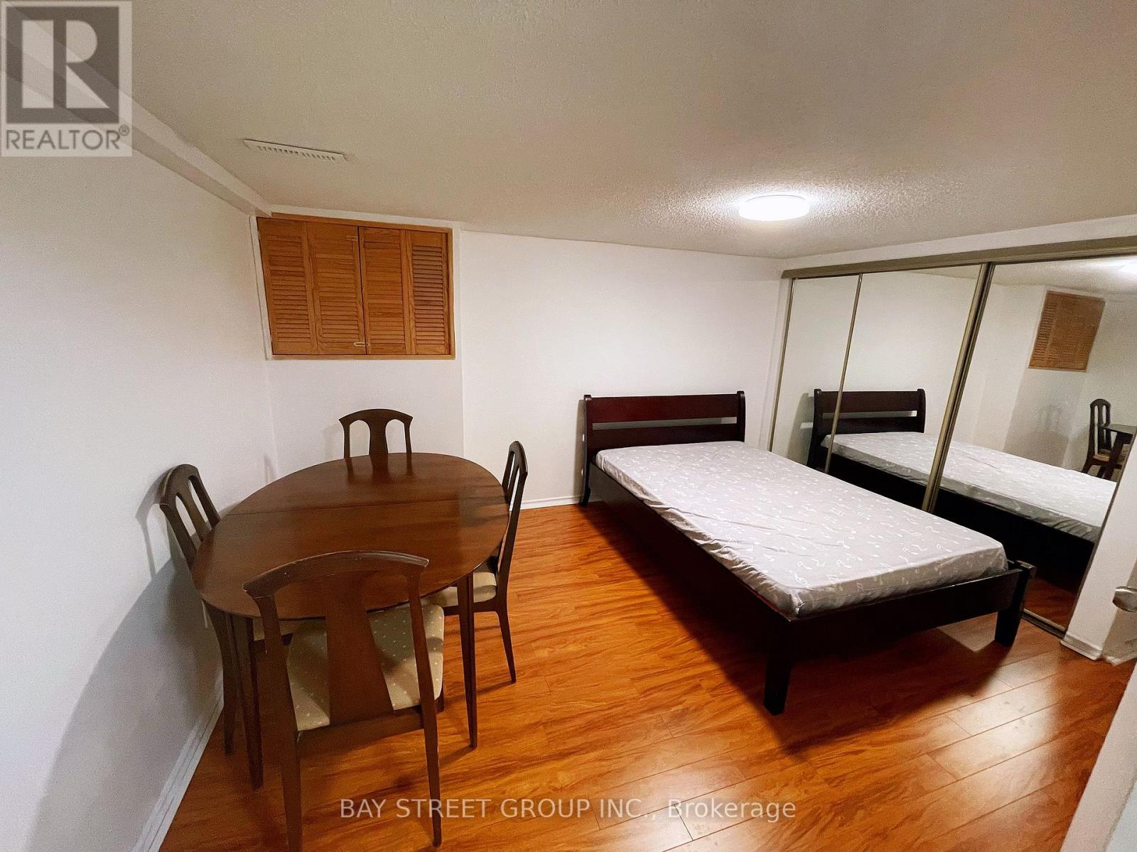 A bedroom with a bed, a table and chairs, and a mirror.