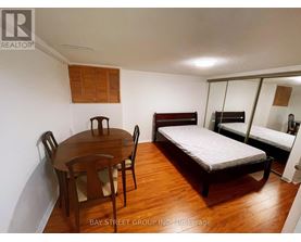 A bedroom with a bed, a table and chairs, and a mirror.