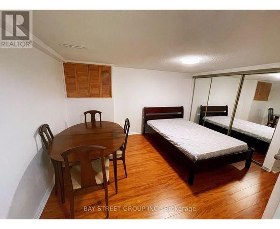 A bedroom with a bed, a table and chairs, and a mirror.