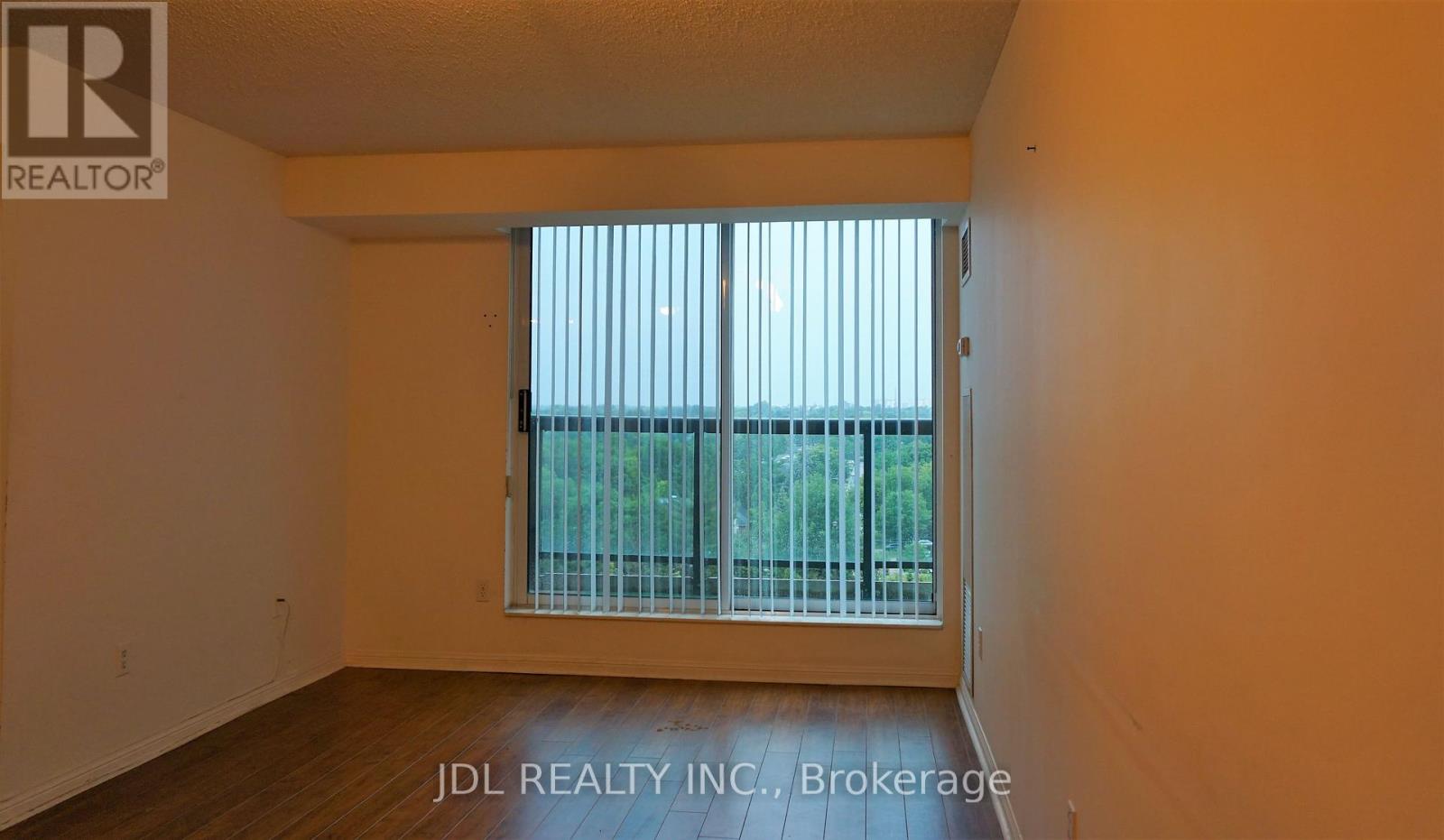 A room with a window and a view of a fence and trees outside.