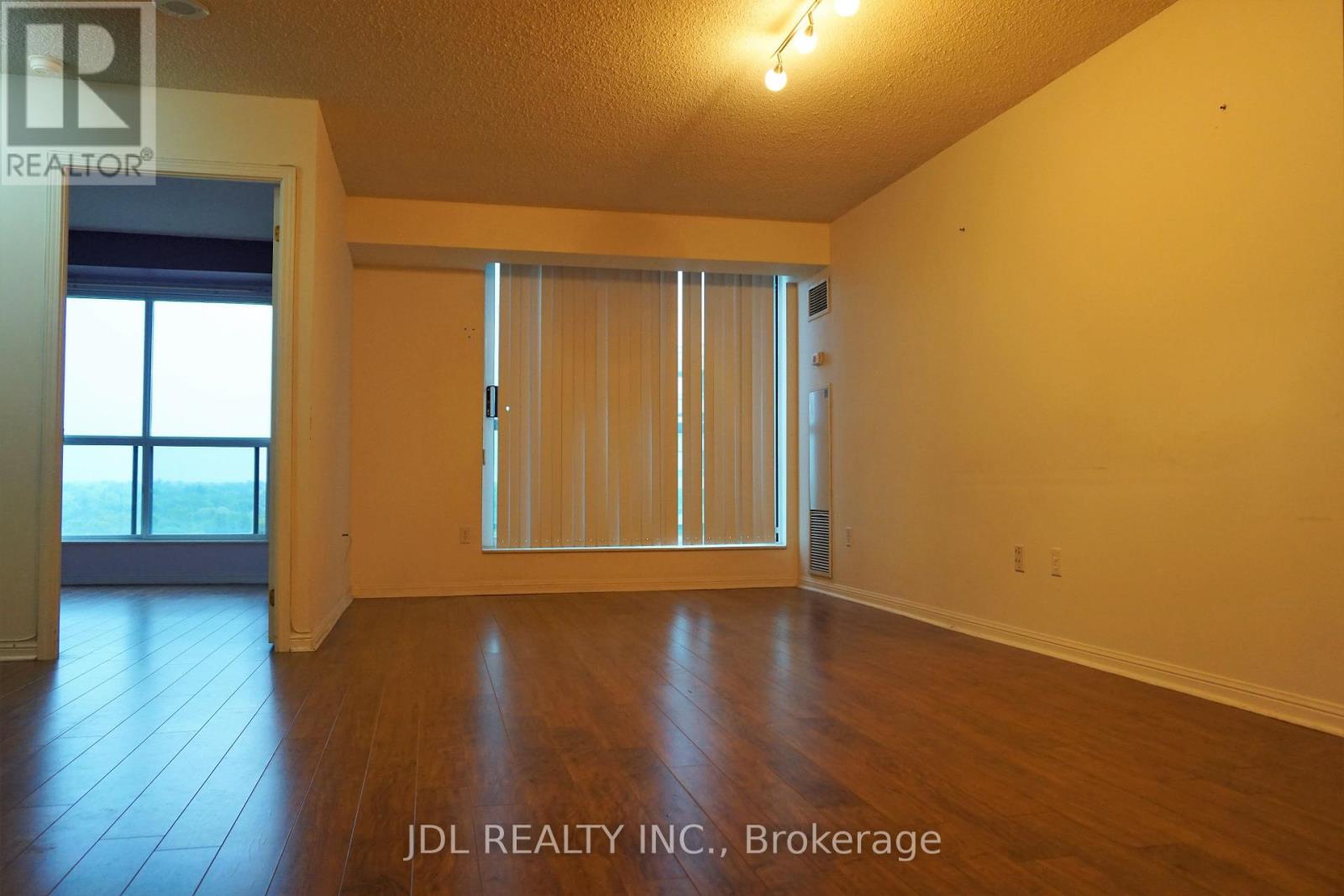 A room with wooden floors and a sliding glass door leading to a balcony.
