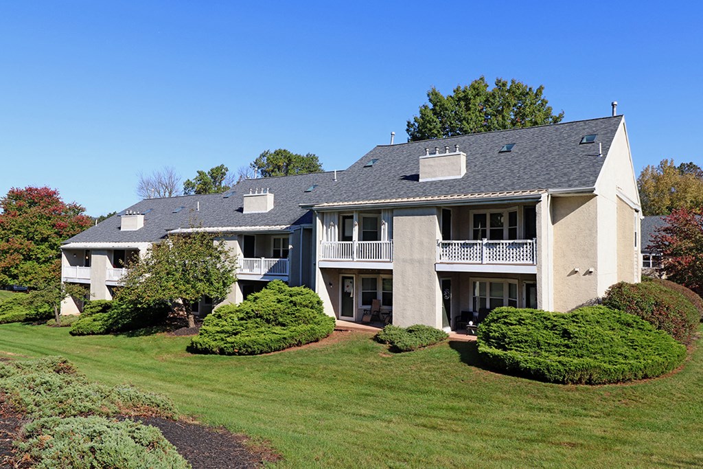 a large house on a hill with a lawn and trees