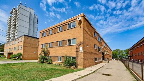 A long brick building with a fence in front of it.
