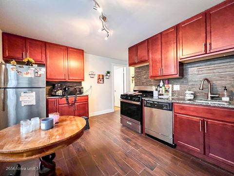 a kitchen with red cabinets and stainless steel appliances