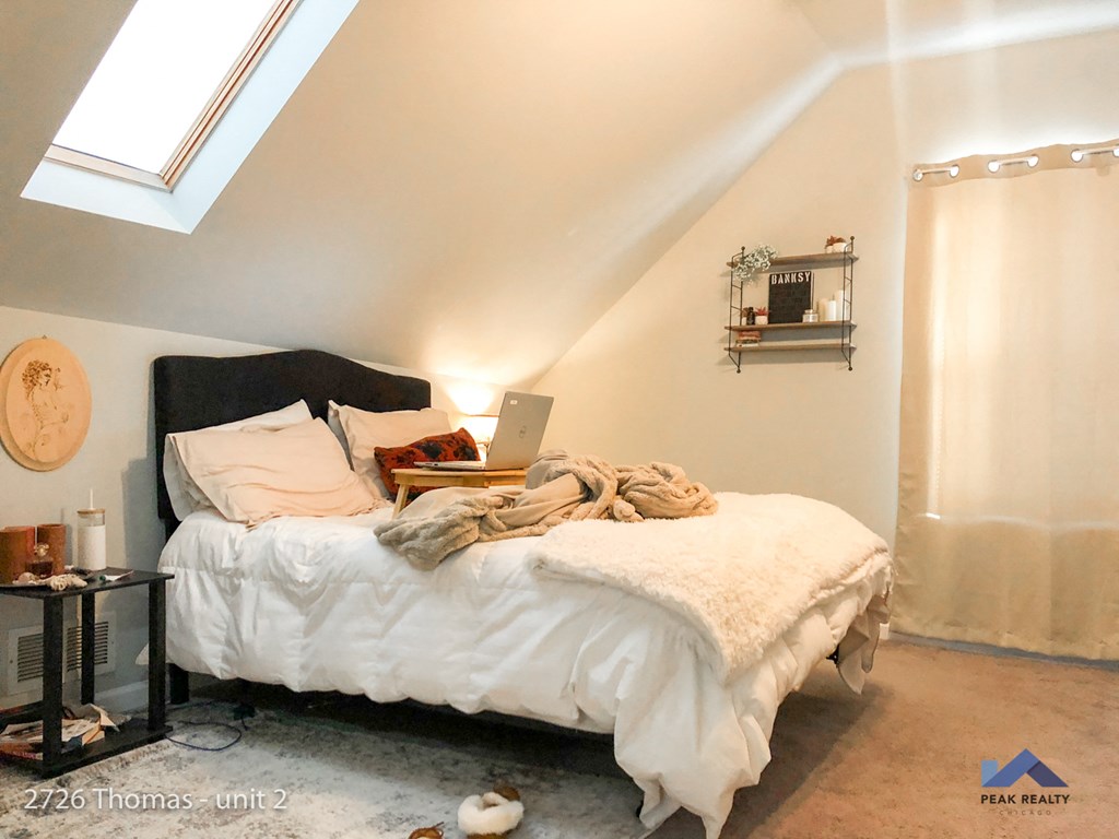 a bedroom with a bed and a laptop on top of it