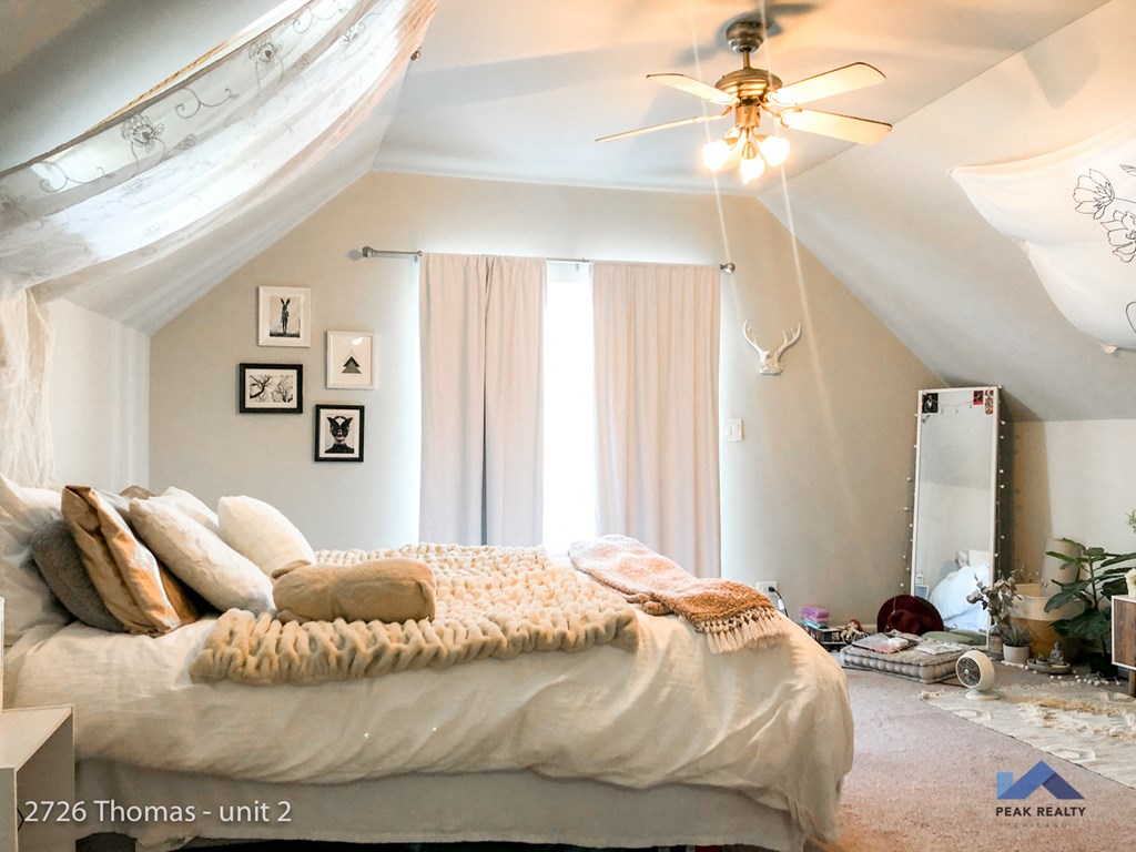 an attic bedroom with a bed and a ceiling fan