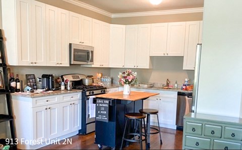 a small kitchen with white cabinets and a table in the middle