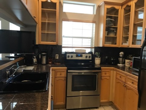 A kitchen with wooden cabinets and black appliances.