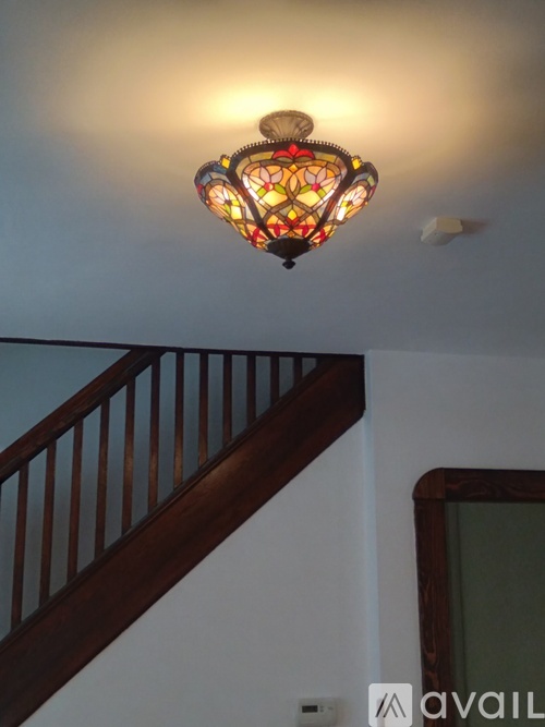 A stained glass lamp hangs over a staircase.