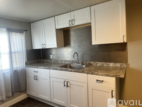 A kitchen with white cabinets and a granite countertop.