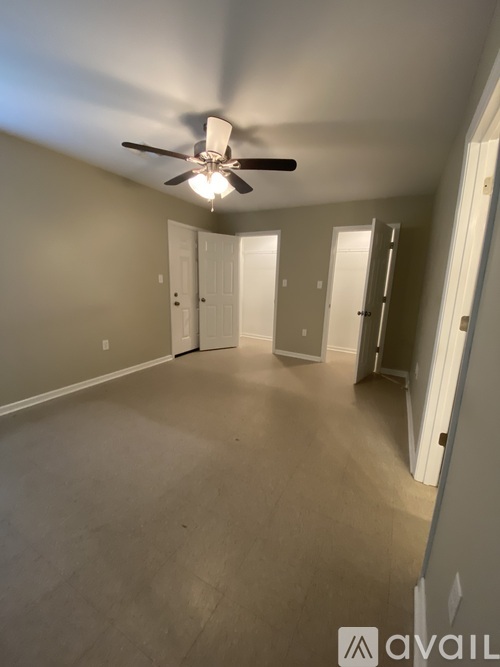 A room with a ceiling fan and light fixture, and three doors.