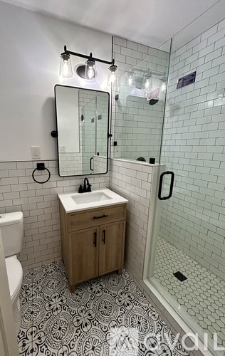 A bathroom with a sink, mirror, and shower.