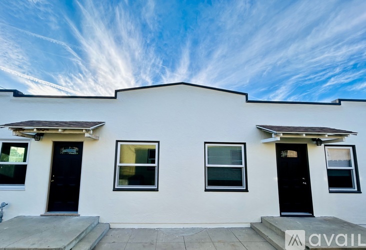 A white house with black doors and windows is for sale.