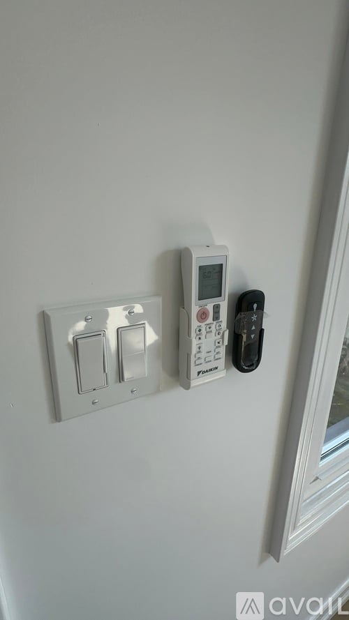 A white light switch plate with three switches and a black remote control.