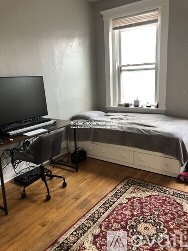 A room with a bed, desk, and chair.