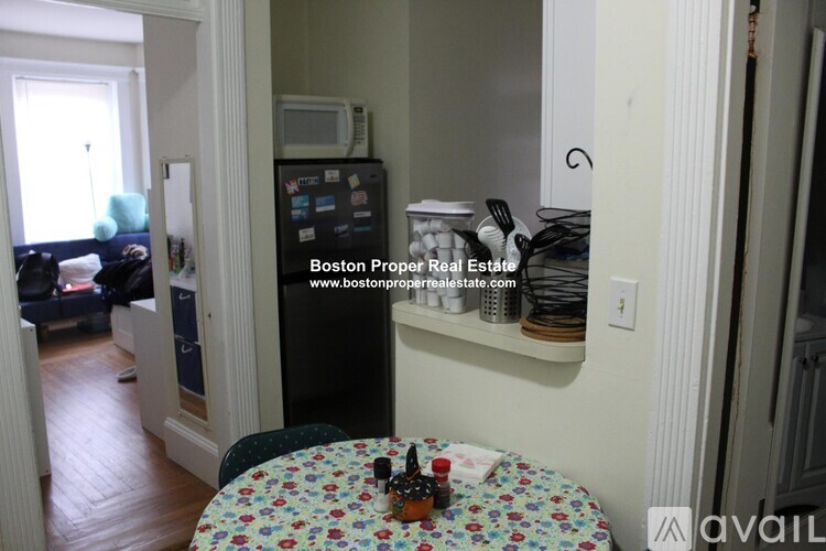 A kitchen area with a fridge, table and chairs.