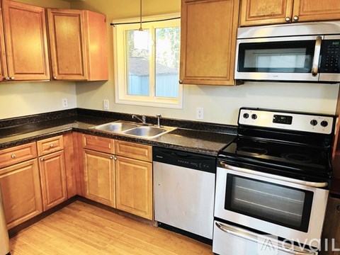 A kitchen with wooden cabinets and a black countertop.