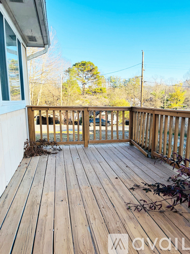 A wooden deck with a railing and a view of the trees.