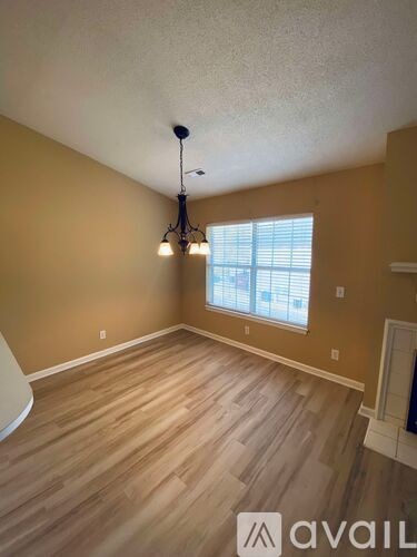 A room with wooden flooring and a chandelier.