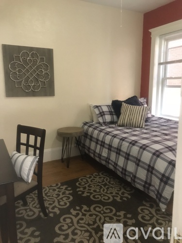 A bedroom with a bed, chair, and a picture on the wall.