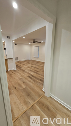 A hallway with wooden floors and white walls.