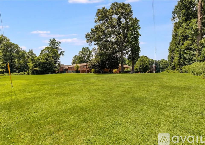 A grassy field with trees and a building in the distance.
