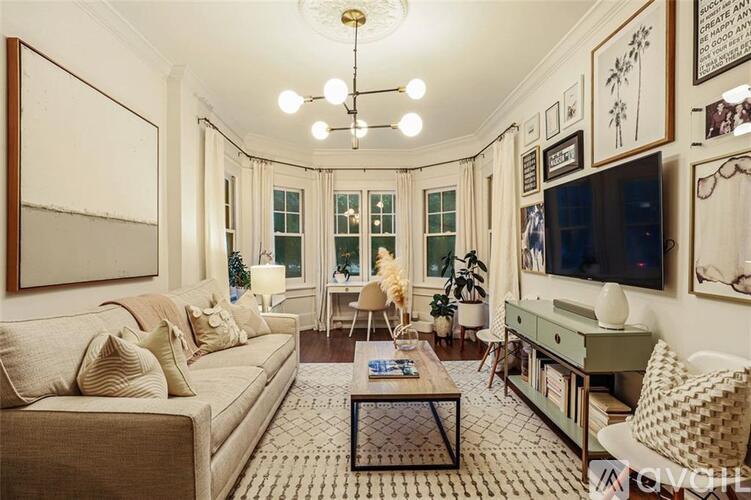 A living room with a beige couch, a coffee table, and a chandelier.