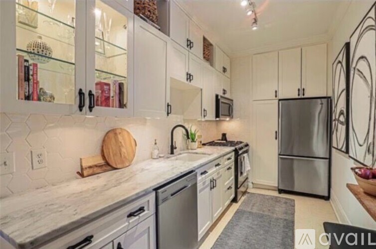 A kitchen with white cabinets and a marble countertop.