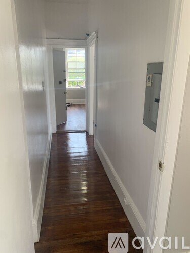 A long hallway with wood floors and white walls.