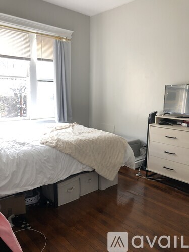 A bedroom with a bed, dresser, and window.