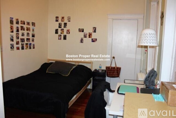A bedroom with a bed, a desk, and a lamp.