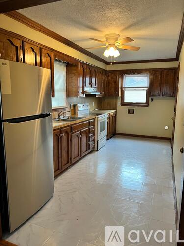 A kitchen with a stainless steel refrigerator and wooden cabinets.