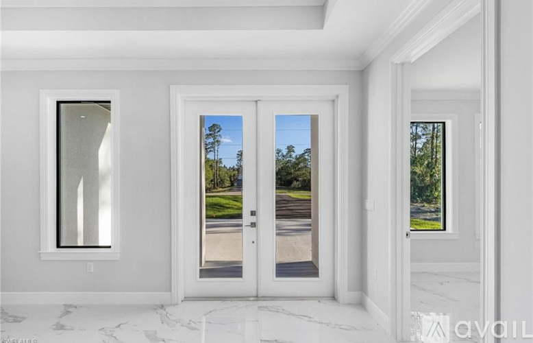 A white interior with a marble floor and a view of a tree-lined street through the glass doors.